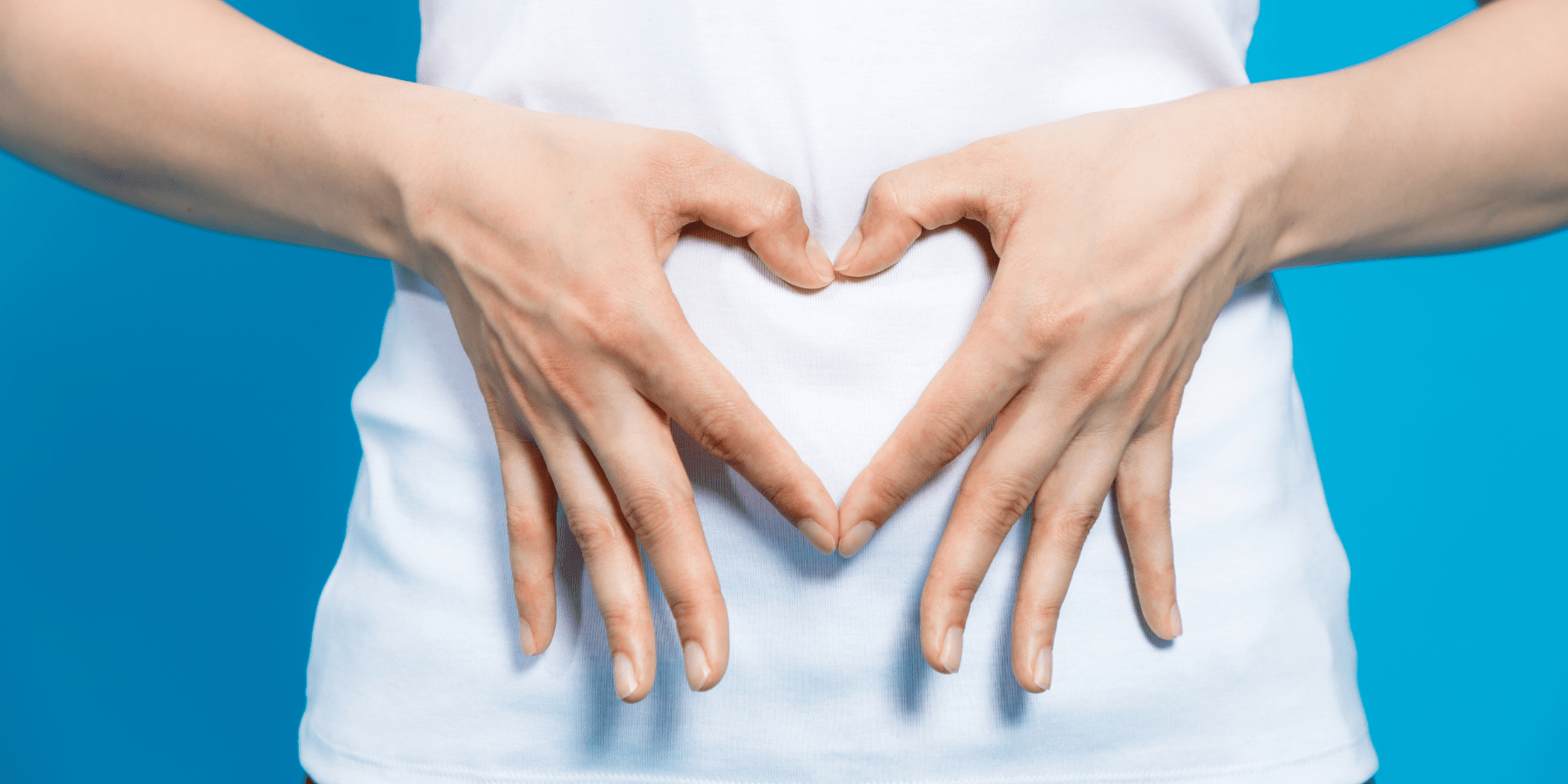Fingers in the shape of a heart on a woman's stomach
